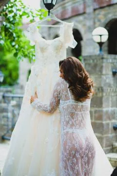 Young beautiful bride preparing to try on her luxury bridal dress Stock Photos
