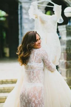 Young beautiful bride preparing to try on her luxury bridal dress Stock Photos