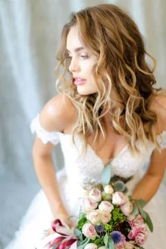 Young beautiful bride wearing white dress with bouquet at photo studio. 스톡 사진