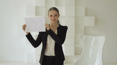 Young beautiful businesswoman showing 80 number on sheet of paper. Stock Footage