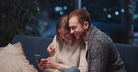 Young beautiful caucasian couple staying home using smartphone social media Stock Footage 148492653
