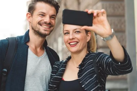 Young beautiful caucasian taking a selfie while on a walk in the city Stock Photos