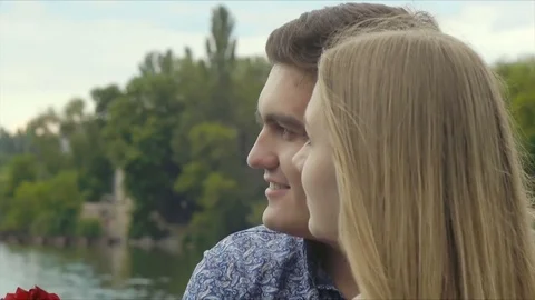 Young beautiful couple on a date standing on a bridge by the lake Stock Footage