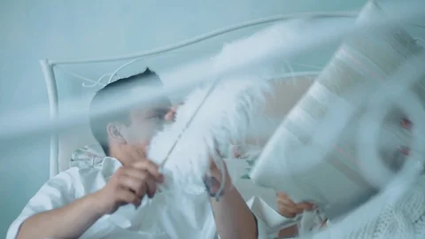Young beautiful couple having fun in bed, they fight by cushions, laughing Stock Footage 105091203