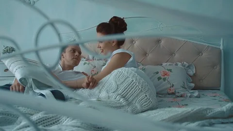 Young beautiful couple having fun in bed, they fight by cushions, laughing, slow Stock Footage 105091306