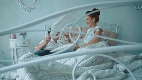 Young beautiful couple having fun in bed, they fight by cushions, passing camera Stock Footage 105091407