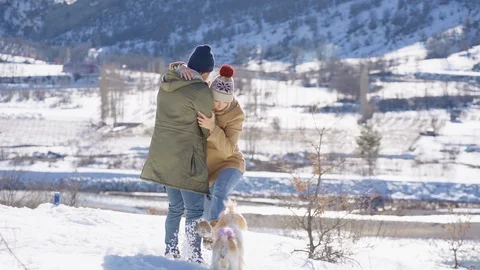 Young beautiful couple having fun with small active dog on a snowy hill Stock Footage 124307776