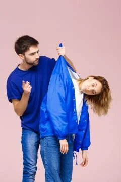 Young beautiful couple posing having fun  over light pink backgroun Fotos Stock