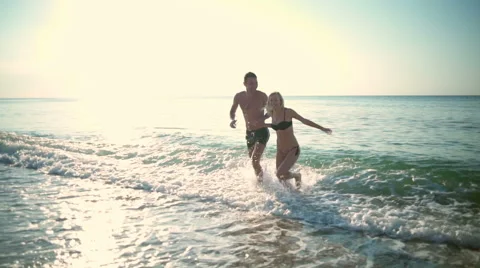 Young beautiful couple smiling going out of ocean. Slow motion. Video stock 68187971
