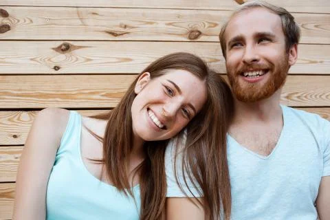 Young beautiful couple smiling, posing over wooden boards background Fotos Stock
