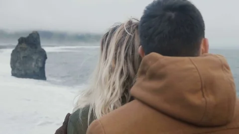 Young beautiful couple standing on the shore of the sea and looking on the troll Stock Footage