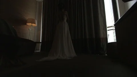 Young beautiful dark-haired bride near the window in hotel room Stock Footage 94211016