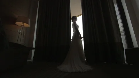 Young beautiful dark-haired bride near the window in hotel room Video stock 94212208