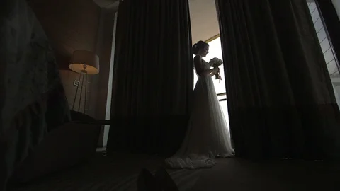 Young beautiful dark-haired bride with bouquet near the window in hotel room Stock Footage 94212212