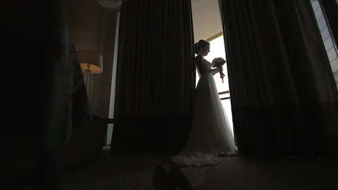 Young beautiful dark-haired bride with bouquet near the window in hotel room Stock Footage 94212240