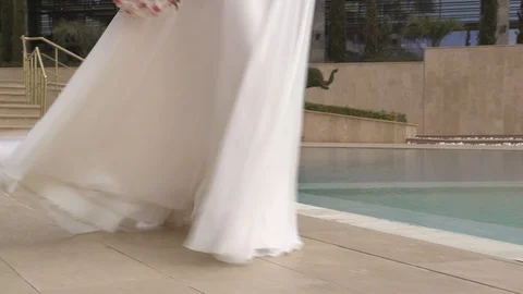 Young beautiful dark-haired bride walking on the hotel territory near pool Stock Footage 94217622
