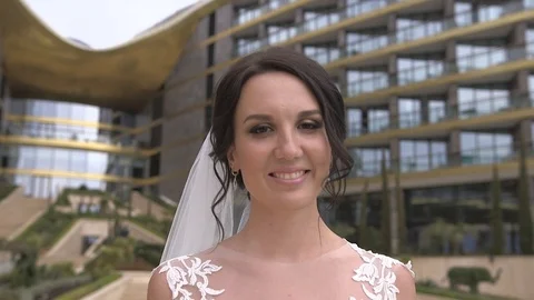 Young beautiful dark-haired smiling bride walking on the hotel territory Stock Footage 94219625