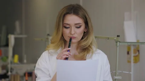 Young beautiful designer thinking in the workplace. Woman keeps sheet of paper Stock Footage 193991522