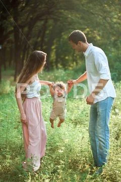Young beautiful father, mother and little toddler son against green trees Stock Photos