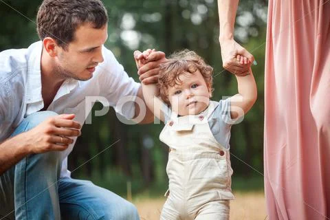 Young beautiful father, mother and little toddler son against green trees Stock Photos