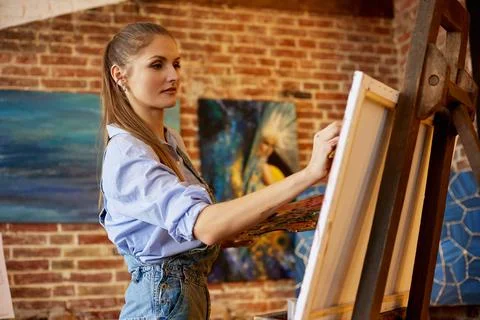 Young beautiful female artist painting on canvas using oil paintings and art Stock Photos