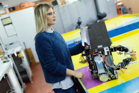 Young beautiful female engineer testing robot in workshop Foto stock