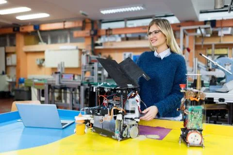 Young beautiful female engineer testing robot in workshop 스톡 사진