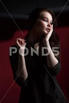 Young beautiful female fashion model in a business stylish suit on a red and Stock Photos