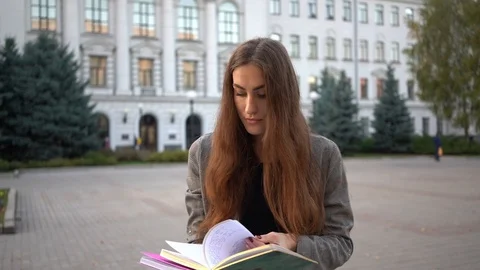 Young beautiful female student in the park outdoors holding books and notebooks Stock Footage