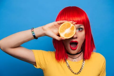 A young beautiful funny model with a slice of orange near her eyes, in the Stock Photos