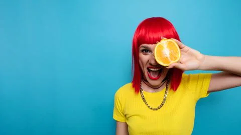 A young beautiful funny model with a slice of orange near her eyes, in the Stock Photos