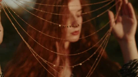 Young beautiful ginger lady looking at camera through the chain necklace. Dolly Stock Footage 124913628