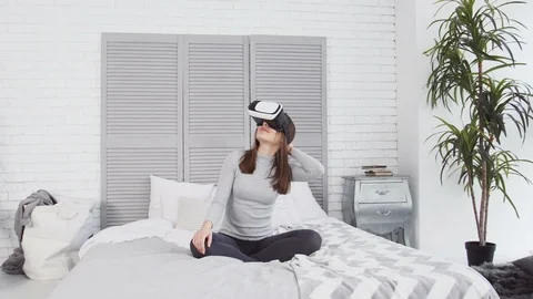 A young beautiful girl on the bed using virtual reality glasses. Stock Footage 86447593