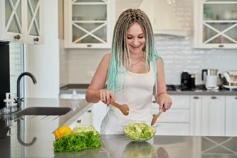 Young beautiful girl with blue dreadlocks cooking salad Stock Photos
