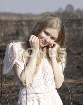 A young beautiful girl in light short-sleeved dress leans her cheek on her fist Stock Photos