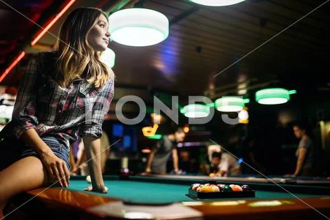 Young beautiful girl is playing billiards. Pleasant pastime, rest, entertainment Stock Photos