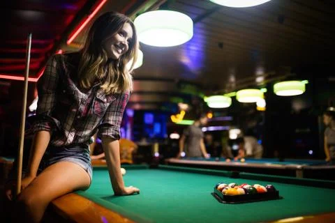 Young beautiful girl is playing billiards. Pleasant pastime, rest, entertainment Stock Photos