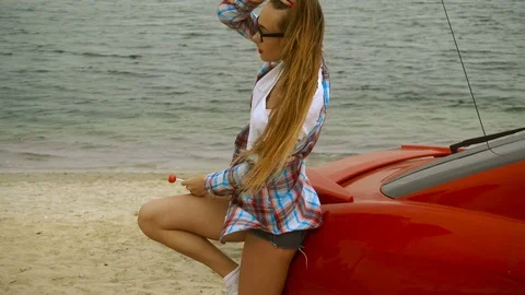 Young beautiful girl with red lips on a seashore licks a lollipop Stock Footage