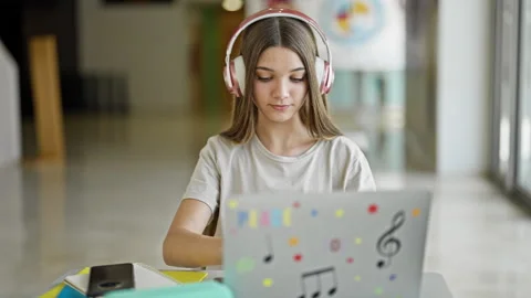 Young beautiful girl student using laptop and headphones studying at library Video stock 247387347