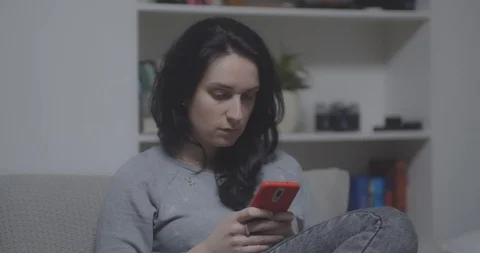 Young beautiful girl using mobile phone at home. Evening time 動画素材 127201888