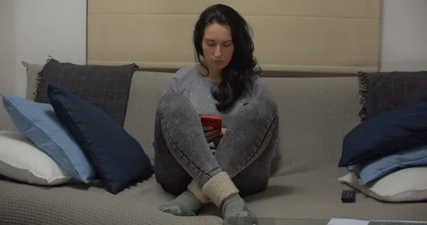 Young beautiful girl using mobile phone at home. Evening time 스톡 동영상 127202169