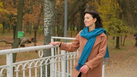 Young beautiful girl walks on the bridge in the park in the fall. Stock Footage