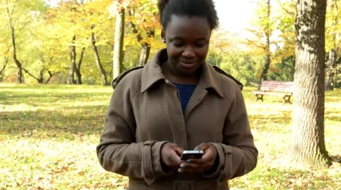 Young beautiful happy african girl walks in the woods, works on phone  Video stock 59798102