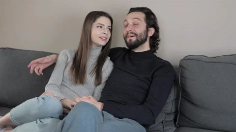 Young beautiful happy couple sitting on the sofa watching a movie Stock Footage