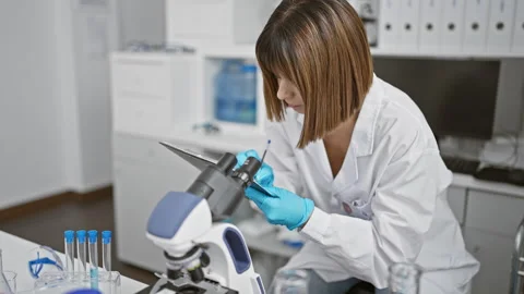 Young beautiful hispanic woman scientist using microscope taking notes at l.. Stock Footage 262193653