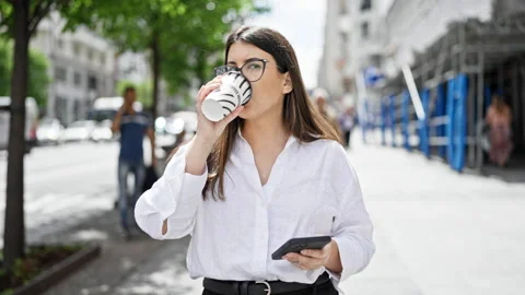 Young beautiful hispanic woman using smartphone drinking take away coffee i.. Video stock 247385891