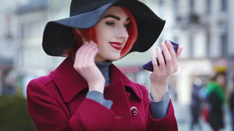 Young beautiful lady correcting her makeup with powder on the street. Stock Footage 61045941