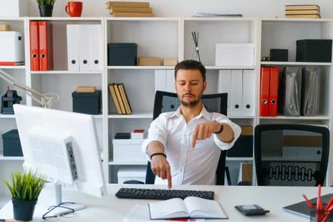 Young beautiful man work on computer sit at table in office smile Stock Photos