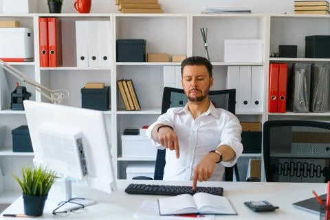 Young beautiful man work on computer sit at table in office smile Foto stock