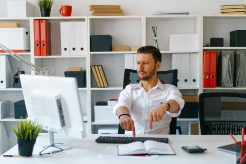 Young beautiful man work on computer sit at table in office smile Stock Photos